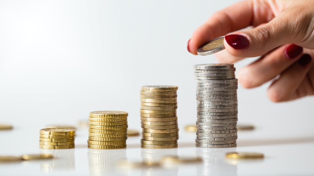 Saving money in piles of coins on white background
